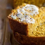 Sliced Buttermilk Pumpkin Spice Bread with spices on a wooden board.