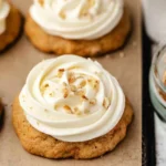 Freshly baked carrot cake cookies with cream cheese frosting and grated carrots