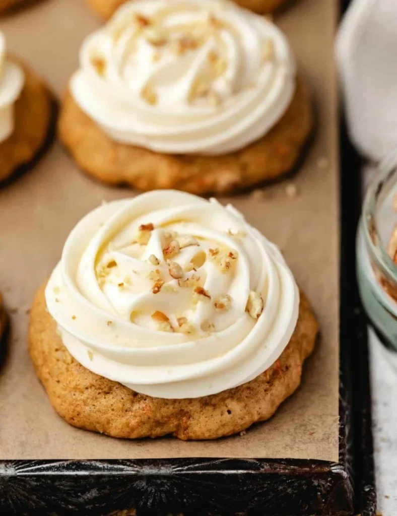 Freshly baked carrot cake cookies with cream cheese frosting and grated carrots