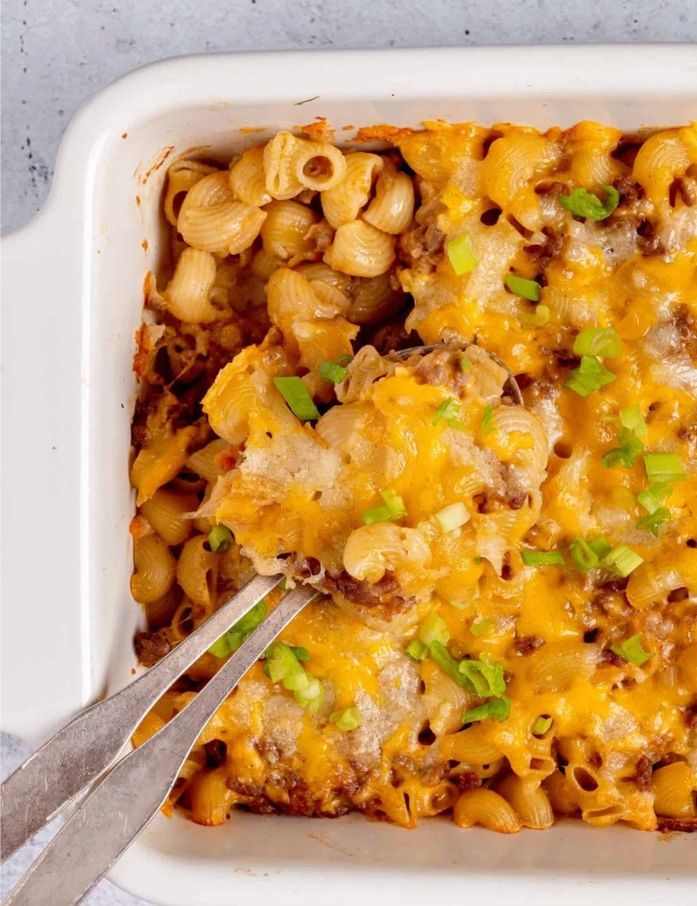 A delicious serving of cheeseburger casserole topped with cheese and herbs.