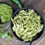 Cilantro pesto chicken salad on a white plate garnished with fresh herbs