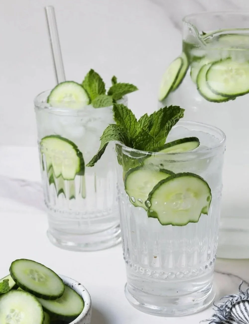 A refreshing glass of cucumber water with slices of cucumber and mint leaves.