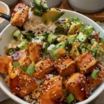 A colorful saucy salmon bowl with vegetables and rice