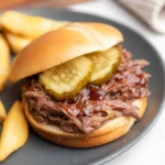 Tender slow cooker barbecue beef served on a plate with a side of coleslaw.