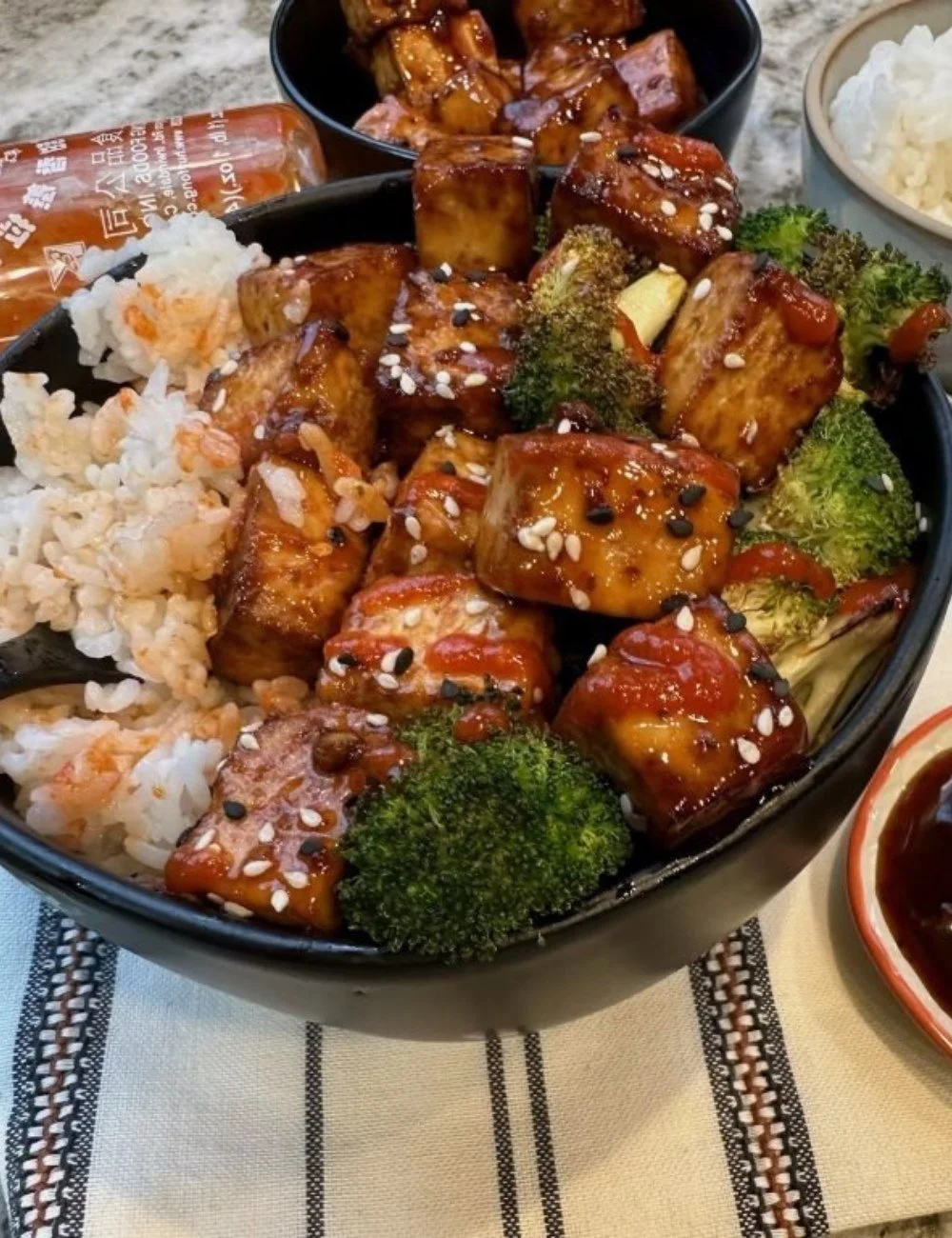 Spicy Sriracha Tofu Bowls garnished with fresh vegetables and herbs