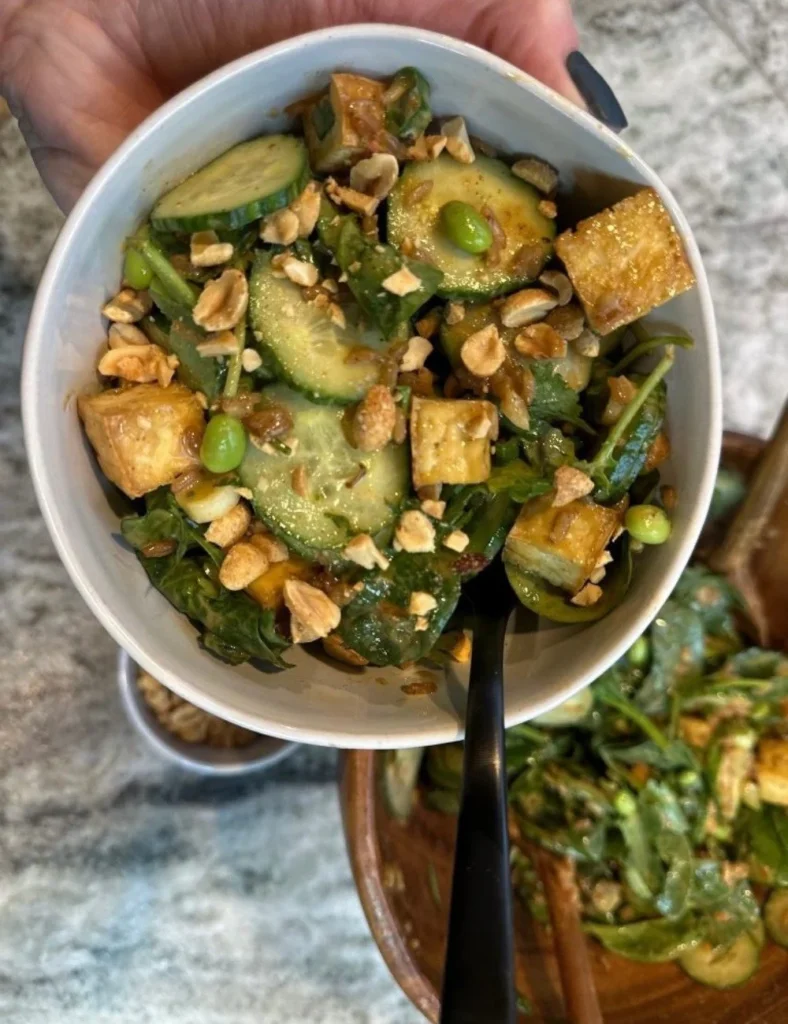 A trendy green salad with fresh vegetables and colorful toppings served in a bowl.