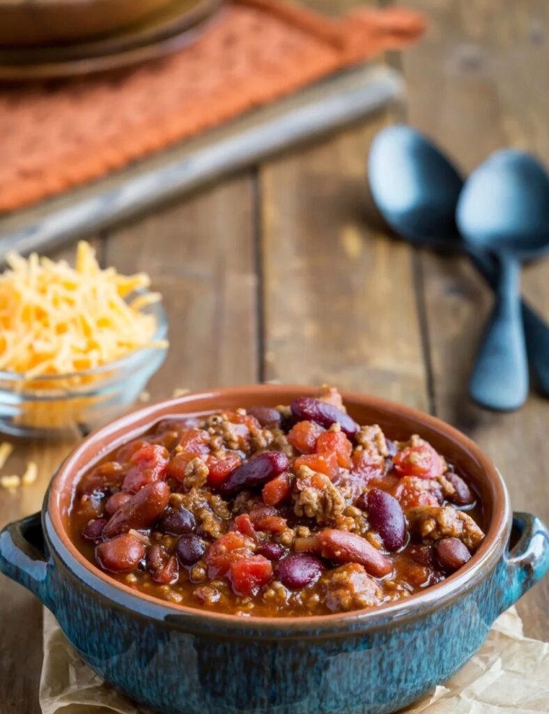 two Bowls of hearty barbecue chili topped with fresh cilantro and served with cornbread