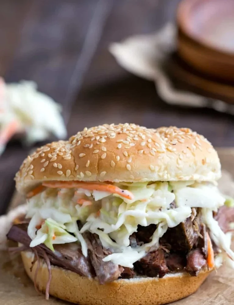 Slow cooker beef sandwiches served with horseradish coleslaw on a plate.